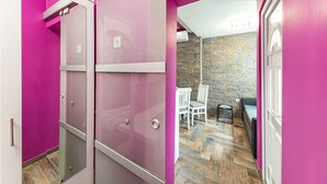 A room with pink walls, a wooden floor, a stone wall, and a dining area with chairs and a table. - Apartments Keka - Studio Apartment (Kastel Sucurac)