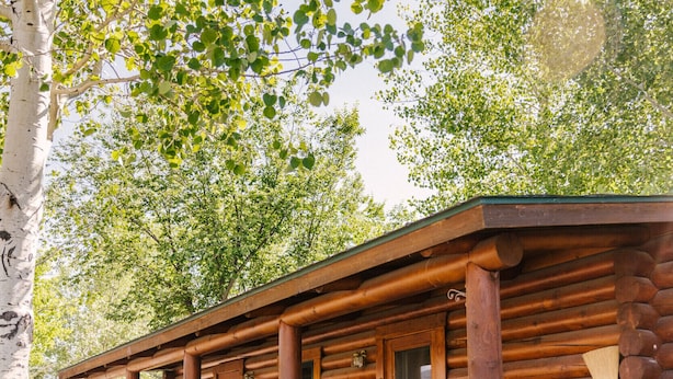 A log cabin with a wooden deck and a single visible window.