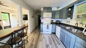 A modern kitchen with grey cabinets, a white microwave, and a stainless steel sink. - Private/Between PF & Knox/DOG friendly/creek/large yard (Seymour)