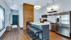 Una cocina moderna con una isla central, electrodomésticos de acero inoxidable y una pared decorada con ladrillos.