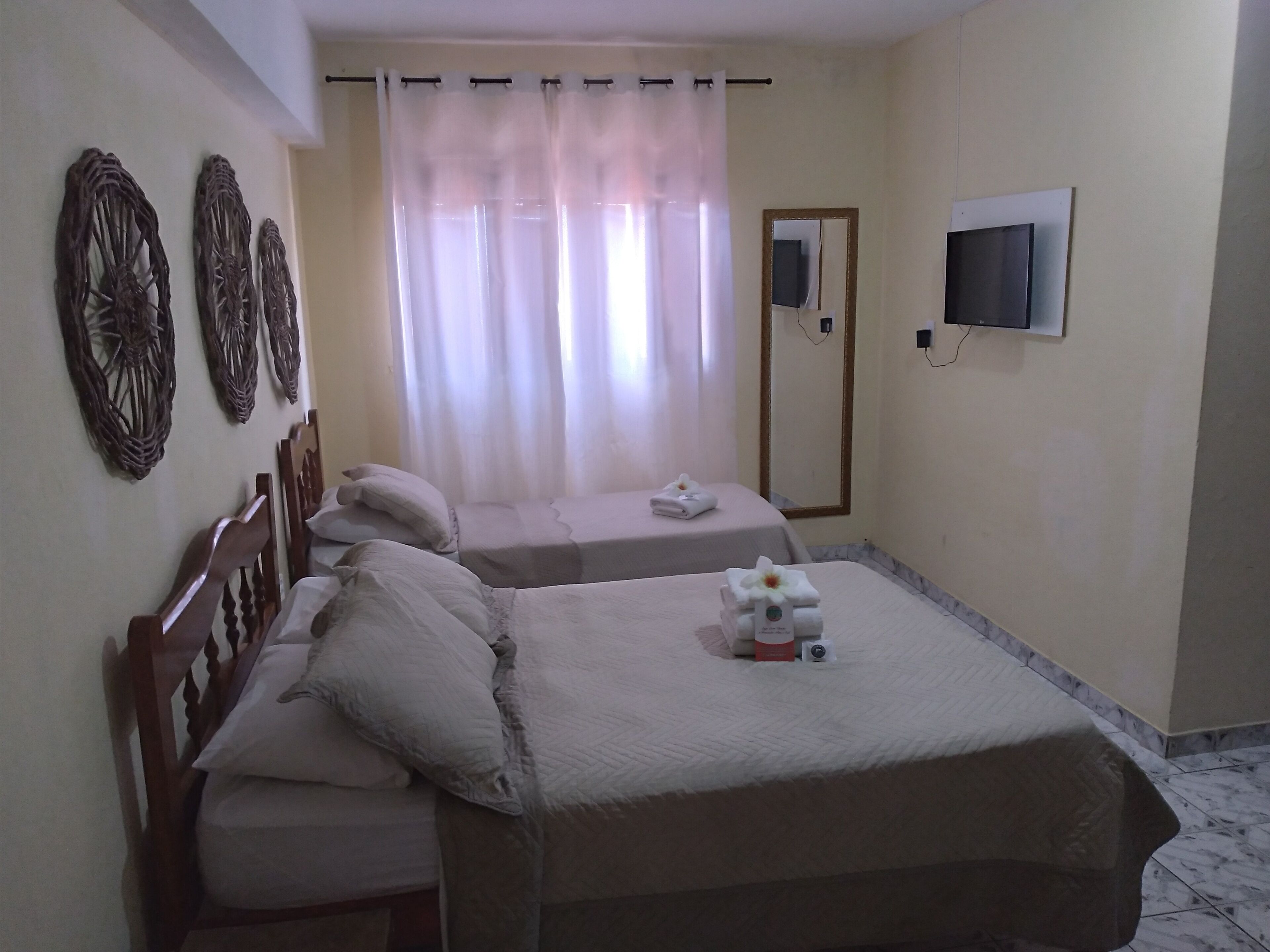 A hotel room with two beds, a TV mounted on the wall, and decorative wall art.