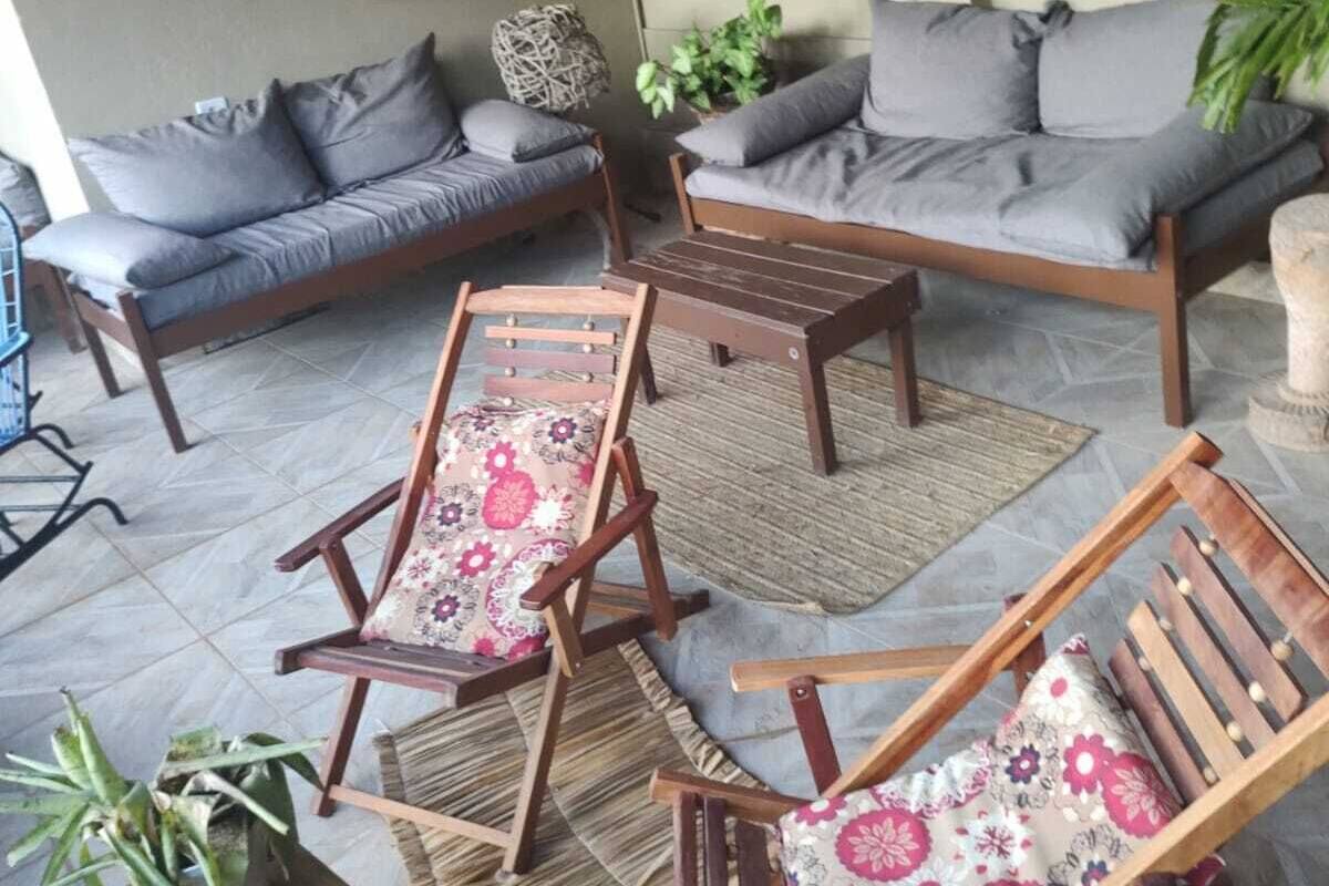 A patio area with two sofas, two wooden chairs, a small table, and a hanging light fixture.