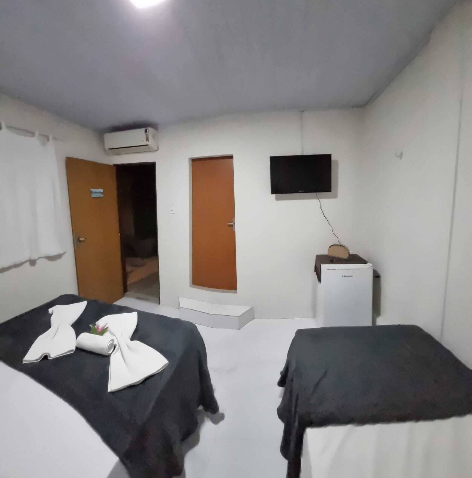Una habitación de hotel con dos camas, televisor, escritorio y aire acondicionado.