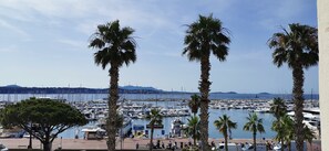 A marina with boats docked, palm trees, and a clear sky. - Apartment with a view of the harbor and the sea, renovated in 2022, 65 m² (Bandol)