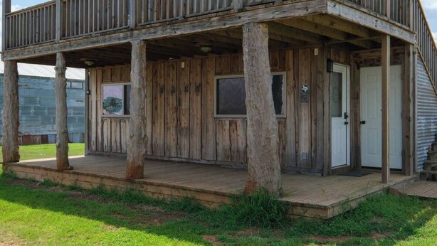 A rustic wooden cabin with a porch, a door, and a window. - Barn 2 @ Yellow Rose Canyon (Mount Enterprise)