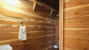 A wooden cabin bathroom with a sink, toilet, and a hanging towel. - Barn 2 @ Yellow Rose Canyon (Mount Enterprise)