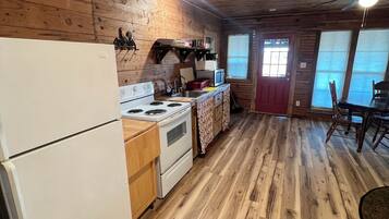 A wooden cabin kitchen with a refrigerator, stove, microwave, and wooden cabinets.