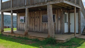 A rustic wooden cabin with a porch, a door, and a window. - Barn 1 @ Yellow Rose Canyon (Rusk County)