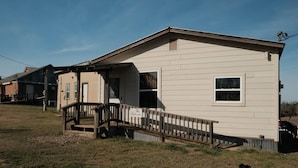 A single-story house with a front porch and a small staircase leading to the entrance. - The Hideout @ Yellow Rose Canyon (Rusk County)