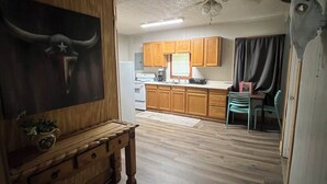 A kitchen with wooden cabinets, a dining area with chairs, and a ceiling fan.