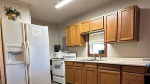 A kitchen with wooden cabinets, a white refrigerator, a stove, and a water dispenser.