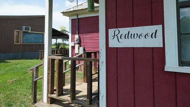 A red building with a sign reading "Redwood" and a stone with "POV RELATIVITY" engraved on it.