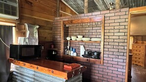 A rustic kitchen with a brick backsplash, wooden counter, and a metal sink.
