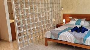 Une chambre à coucher comprenant un lit, une table de chevet, une lampe fixée au mur et un panneau décoratif.