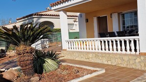 Une maison avec une terrasse carrelée, une balustrade blanche et un palmier.