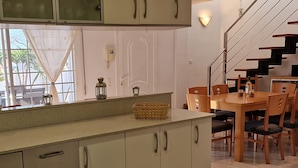 Une cuisine avec un coin repas, un escalier et une vue par la fenêtre.