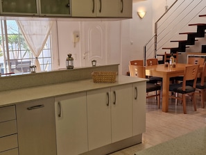 A kitchen with a dining area, a staircase, and a view through the window.