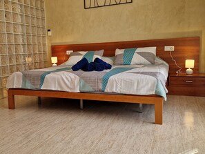 A neatly made bed with a wooden frame, a patterned bedspread, and two bedside lamps.