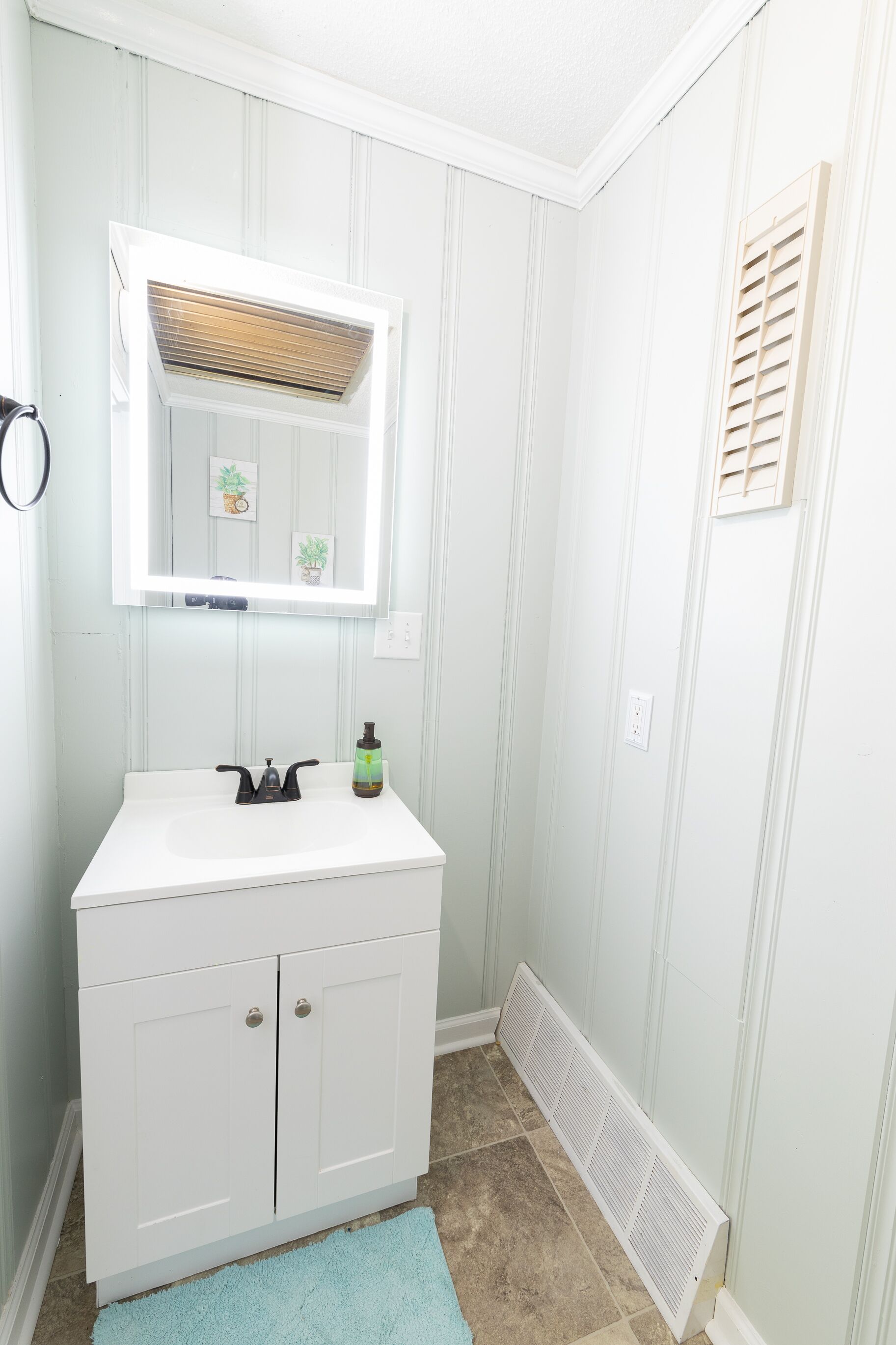 Une salle de bain avec un meuble-lavabo blanc, un miroir, un porte-serviettes et un radiateur.