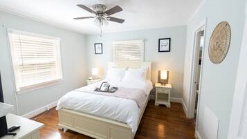 Ein Schlafzimmer mit Bett, Nachttischen, Deckenventilator und einer Wanddekoration.