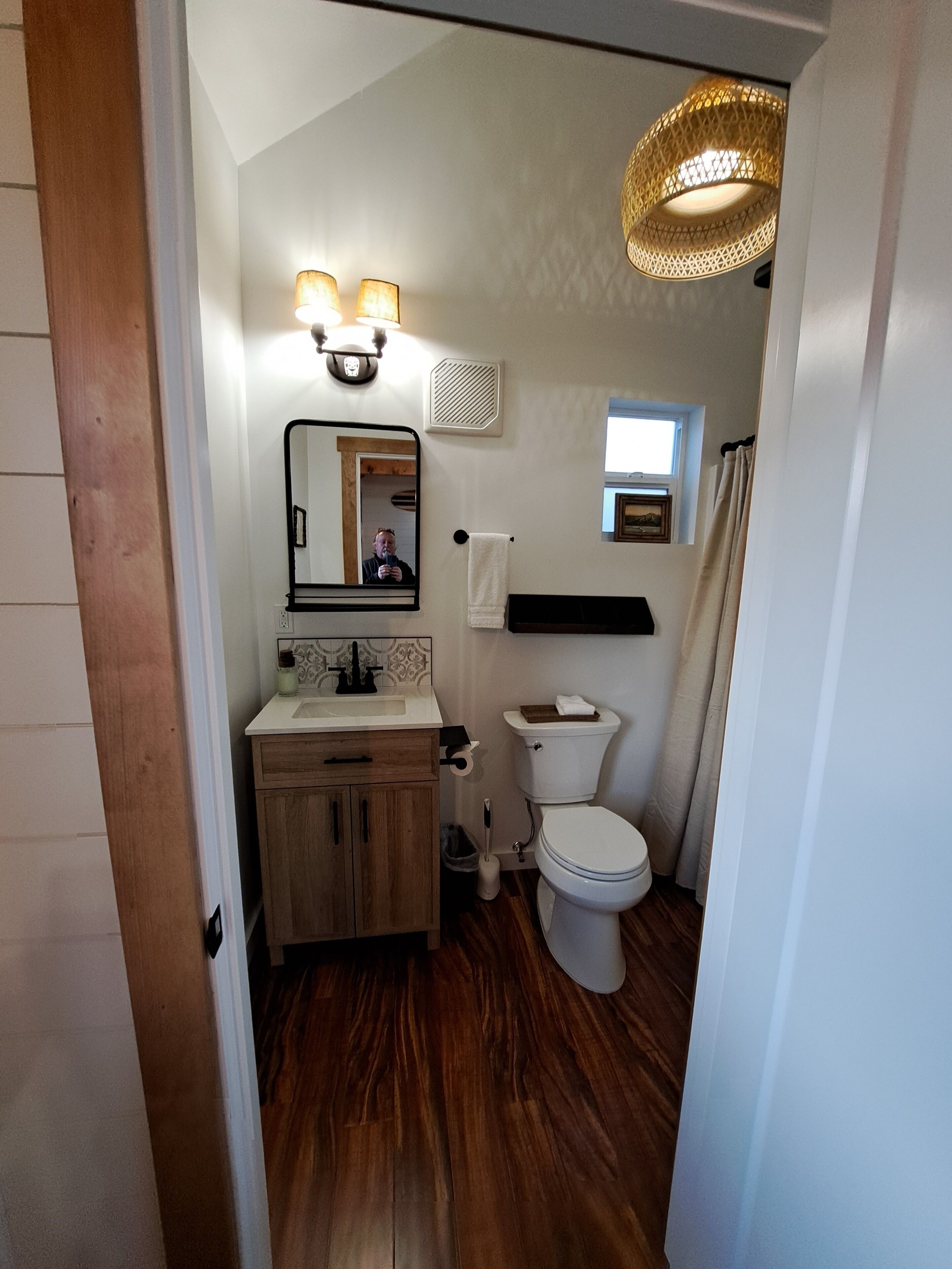 Une petite salle de bain avec un meuble-lavabo en bois, des toilettes et un rideau de douche.