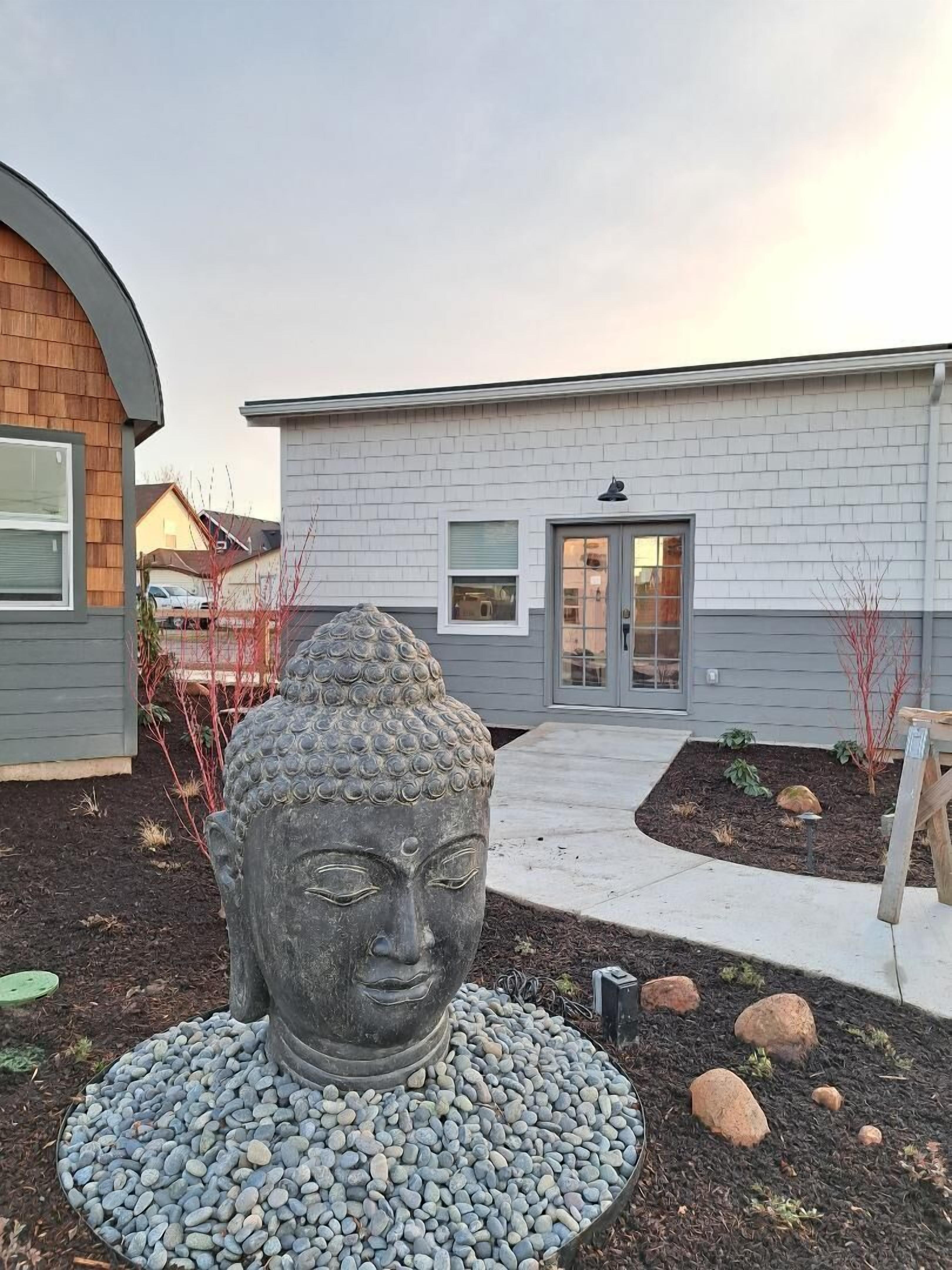 A modern building with a stone Buddha statue in the front garden.