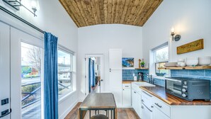 Una cocina moderna con techo de madera, armarios blancos y un comedor con mesa y sillas.