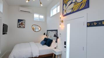 Un dormitorio con cama, mesita de noche y lámpara en el techo.