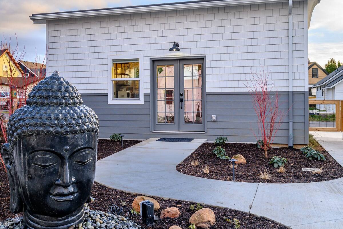 A modern two-story house with a gray exterior, a front door, and a small window.