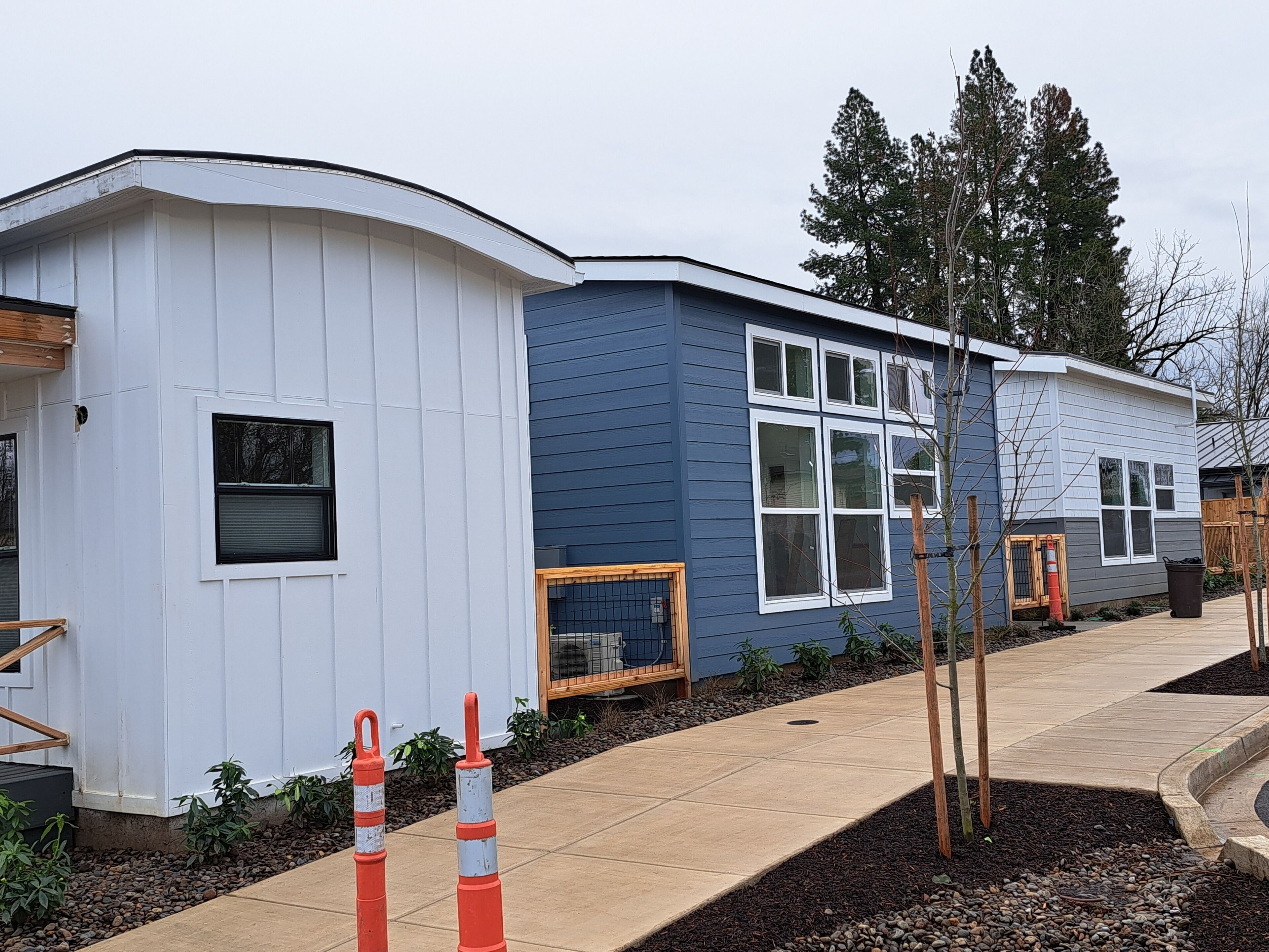 A two-story building with a white and blue exterior, a covered porch, and a paved walkway.