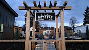 Una pérgola de madera con un letrero que dice "The Boutique Retreat Tiny House Hotel" y un área con fogata.