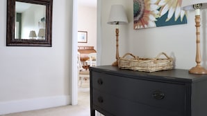 Una habitación con un aparador oscuro, una cesta de mimbre, una lámpara y un espejo en la pared.
