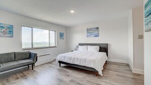 Ein Schlafzimmer mit einem großen Bett, einer Couch, einem Fenster mit Blick und Kunstwerken an den Wänden.