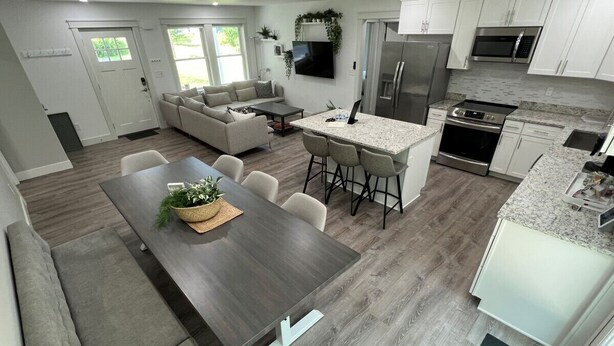 A modern kitchen with a central island, built-in appliances, and a dining area with a long table and chairs.