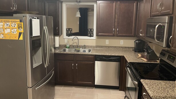 A modern kitchen with stainless steel appliances, dark wooden cabinets, and a granite countertop. - Home away from home 37043 (Clarksville)