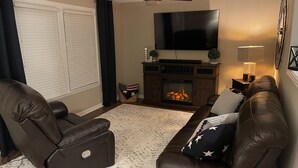 A living room with a fireplace, leather sofas, a flat-screen TV, and a ceiling fan. - Home away from home 37043 (Clarksville)