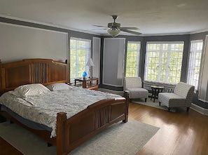 Relax in this serene bedroom with a large bed, armchairs, and a small table.