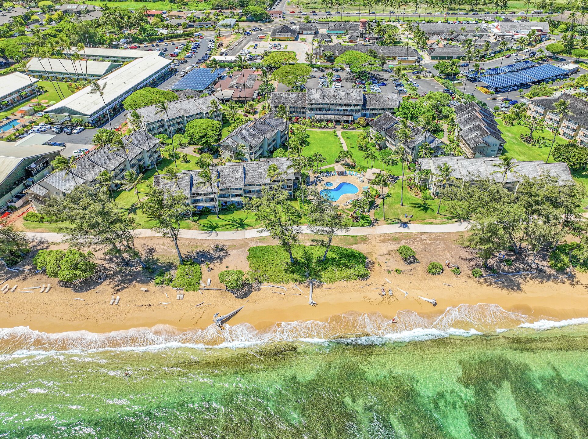 An aerial view of a resort with multiple buildings, a swimming pool, and a beach.