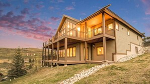 Et toetagers hus med balkon, store vinduer og en stensti, der fører til indgangen.
