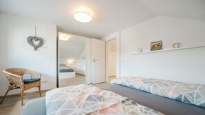 Un dormitorio con cama, una silla y un armario.