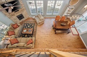 Relax in a spacious living area with a high ceiling, large windows, and a cozy seating area featuring a sofa and chairs.