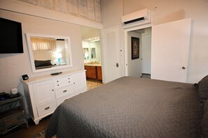Quarto com cama, cômoda, espelho e ar condicionado.