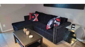 Ein Wohnzimmer mit einem dunkelgrauen Sofa, einem Couchtisch und einem Beistelltisch mit einer Lampe.