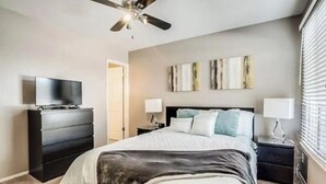 Ein Schlafzimmer mit Bett, Kommode, Fernseher und Bildern an der Wand.