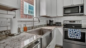 Una cocina moderna con armarios blancos, un lavamanos de acero inoxidable, un microondas y un horno.
