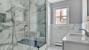 Un baño moderno con ducha de vidrio, inodoro y lavamanos.