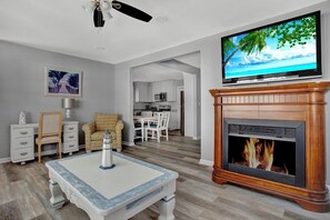 A living room with a fireplace, a television, and a dining area.