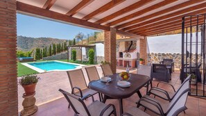 An outdoor patio with a pool, dining table, and chairs, surrounded by stone walls and greenery. - Casa La Fuente Pinta Arenas by Ruralidays (Málaga)