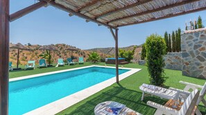 A swimming pool with lounge chairs and a stone wall. - Casa La Fuente Pinta Arenas by Ruralidays (Málaga)