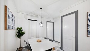 A modern dining area with a white table, black chairs, a hanging light fixture, and a potted plant. - Shorehaven 2- Updated and Stylish 2 bedroom 14 St! (Ocean City)